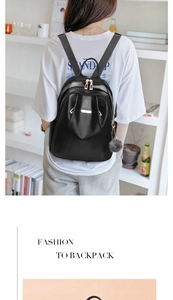 Detail of fashion black leather backpack with gold zipper and gray fur pompom accessory