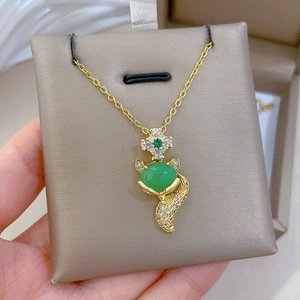 Macro view of golden fox pendant with green zircon stone and sparkling pavé diamonds