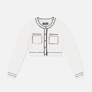 Detail of white tweed jacket featuring black fringe trim and textured knit fabric