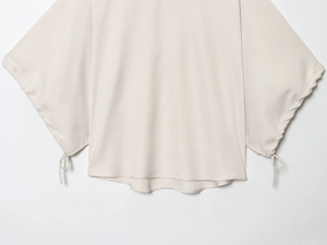 Close-up of drawstring cuff details and woven texture on beige puffed sleeve blouse