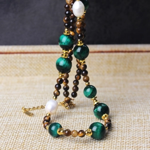 Macro detail of tiger eye beads, green agate, and pearls on a straw-textured stand