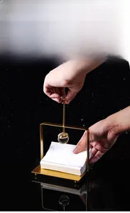 Close-up of golden metal napkin holder featuring a crystal-decorated weighted press arm