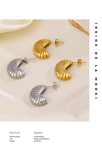 Detailed view of 18K gold and silver pleated fan stud earrings on soft white satin silk