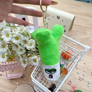 Close-up of a cute green onion plush keychain with sunglasses embroidery and metal ring