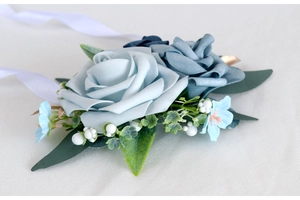 Detail of light blue rose wrist corsage with white silk ribbons and delicate greenery
