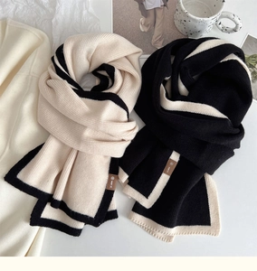 Detailed view of knitted scarf texture and brown brand label on high-density fabric