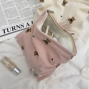 Detail of pink corduroy makeup bag with cute bear embroidery and metal zipper closure