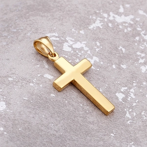 Close-up of polished gold cross pendant on a textured gray background with soft lighting