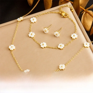 Detailed set of gold flower necklace, bracelet and earrings on champagne silk background