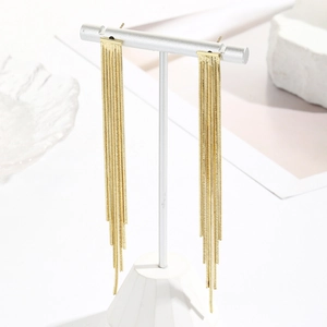 Detail of long gold tassel earrings with rhinestone chains on a white display stand