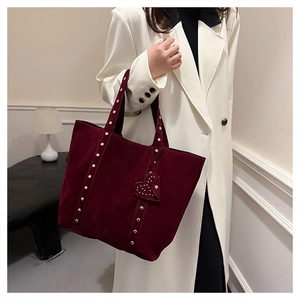 Close-up of burgundy suede tote bag with stylish rivet details and heart pendant