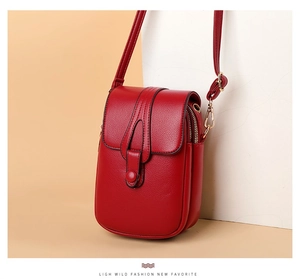 Macro shot of red pebble leather phone bag with gold zipper and adjustable shoulder strap