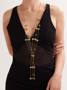 Detail of long gold stainless steel heart necklace with agate beads on a black dress