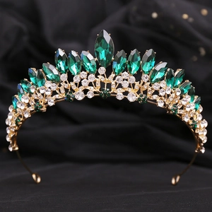 Luxurious bridal crown with emerald gemstones and sparkling crystals on golden metal base