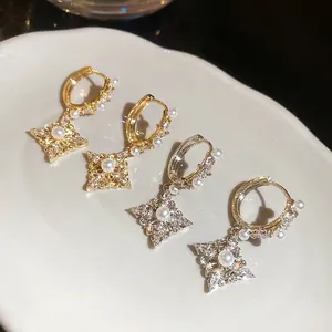18K gold plated zircon star drop earrings with white pearls on a ceramic plate