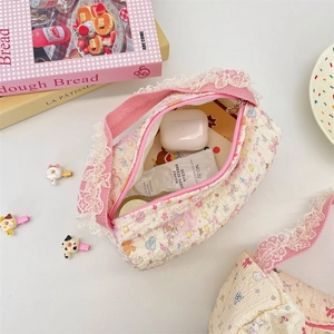 Detail view of floral quilted canvas pouch with white lace trim and zipper closure