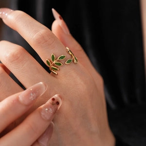 Macro shot of an adjustable gold-plated leaf ring with green enamel details on a model hand