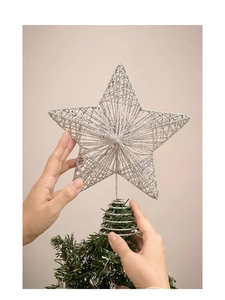 Close-up of placing a silver glittered wire mesh star topper onto a Christmas tree