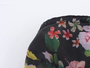 Detail of floral organza dress showing black fabric with colorful flowers and fine stitching