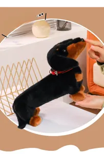 Close-up of a plush dachshund dog toy with soft black and tan fur and a red collar detail