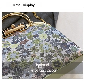 Close-up of floral jacquard fabric and gold metal clasp on a vintage crossbody bag