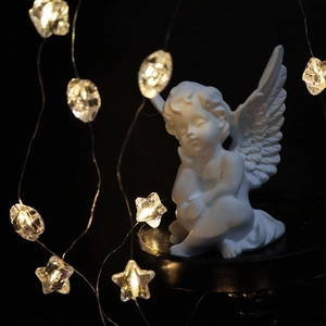 White angel sculpture ornament with warm star LED string lights for Christmas decor