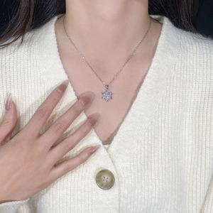 Detailed close-up of a silver snowflake pendant necklace with zircon on a model