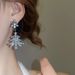 Detail of Christmas tree earrings with snowflakes, pearls, and tassels on model's ear
