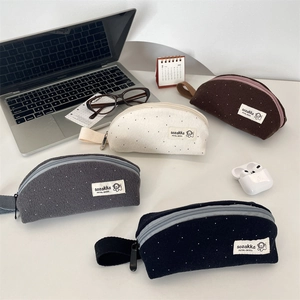 Polka dot woolen fabric pencil cases in various colors on a modern office desk