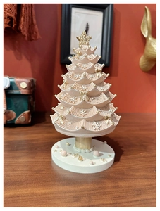 Detailed close-up of pink and white Christmas tree music box with gold stars on wood