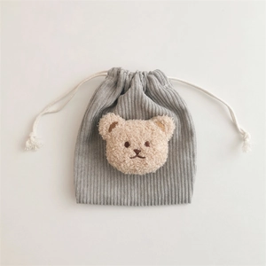 Macro view of grey corduroy drawstring bag with a 3D plush bear decorative detail
