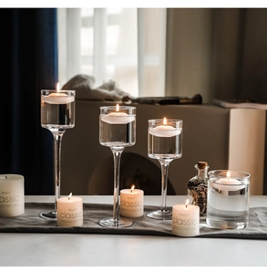 Portacandele alti in vetro con candele galleggianti per un'atmosfera di cena romantica