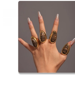 Detailed close-up of 18K gold plated teardrop rings with brown wood grain stones