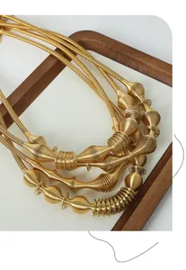 Detailed close-up of multilayered spiral gold necklace with refined spring texture