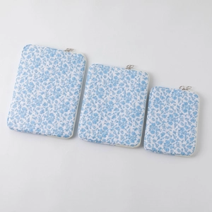Three sizes of quilted floral laptop sleeves in blue and white with metal zippers