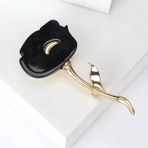 Detail of elegant black enamel rose brooch with golden leaves on a white background