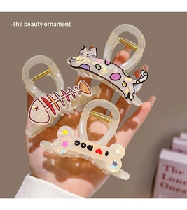 Detail of pearlescent cartoon cat and fishbone claw clips with holographic finish