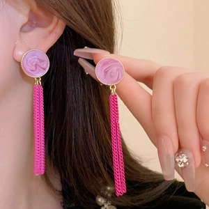 Close-up of pink marble stud earrings with long metal tassel chains on a model