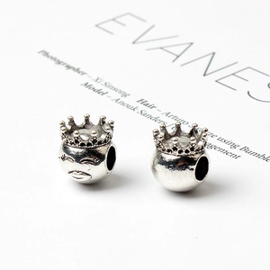 Detail shot of silver crown charms and facial reliefs for DIY charm bracelet beads