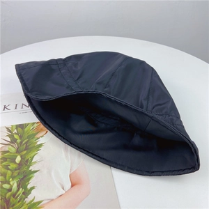 Classic black minimalist bucket hat for sun protection on white table with a magazine