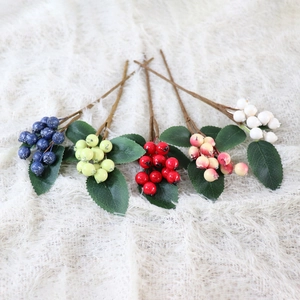 Detailed view of artificial berry stems in five colors with realistic green leaves