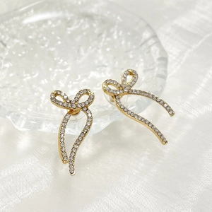 Macro view of gold bow earrings with micro-set rhinestones and elegant long tassels