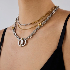 Détail d'un collier multicouche en acier titane avec maillons trombone dorés et argentés