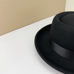 Détail d'un chapeau fedora classique en feutre noir avec ruban côtelé et bord plat