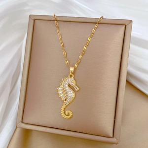 Close-up of a gold seahorse pendant with clear crystals on white silk inside a jewelry box
