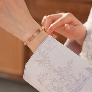 Macro detail of natural red quartz beaded bracelet worn with elegant silk sleeve