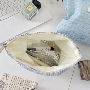 Blue plaid canvas makeup bag showing interior storage capacity for toiletries