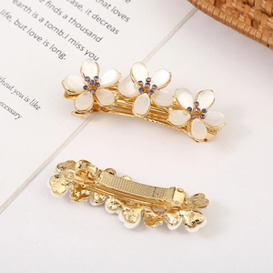 Floral hair clips set with opal petals and purple crystals on a gold-tone base