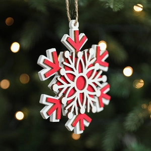 Red and white Nordic wooden snowflake ornament hanging on a Christmas tree with warm bokeh