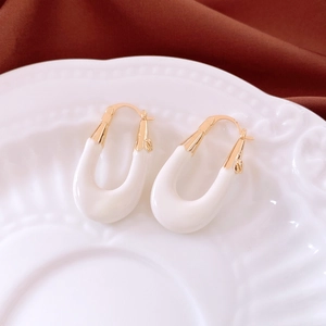 Detail of white U-shaped vintage earrings on a ceramic plate with red background
